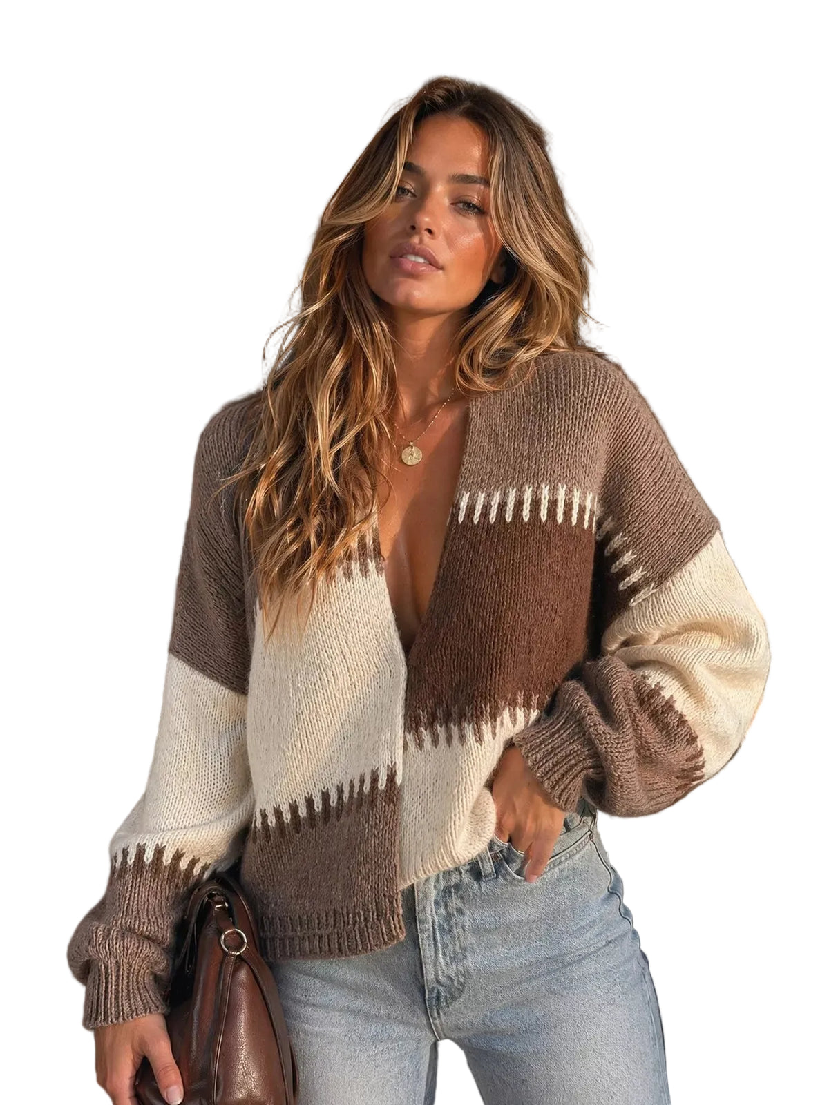 A woman wearing a cozy knit cardigan with brown, cream, and beige geometric patterns, paired with light blue jeans, standing in front of a rustic wooden door.