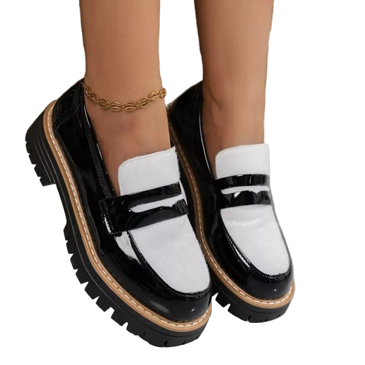 A pair of chunky platform loafers with a black and white color-blocked design, glossy patent leather toe caps, and a thick lug sole, shown on a model's feet.
