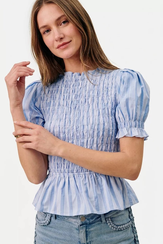 Woman wearing a blue and white striped blouse with puffed sleeves on a white background