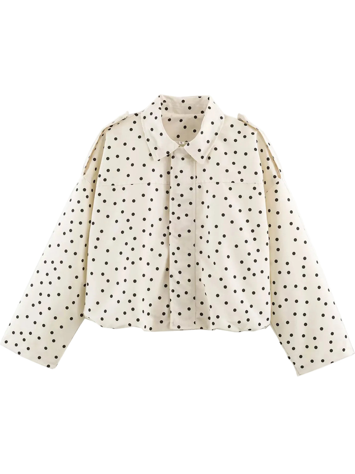 An off-white long-sleeve blouse with a black polka dot pattern, featuring a pointed collar and shoulder epaulets, shown against a plain white background.