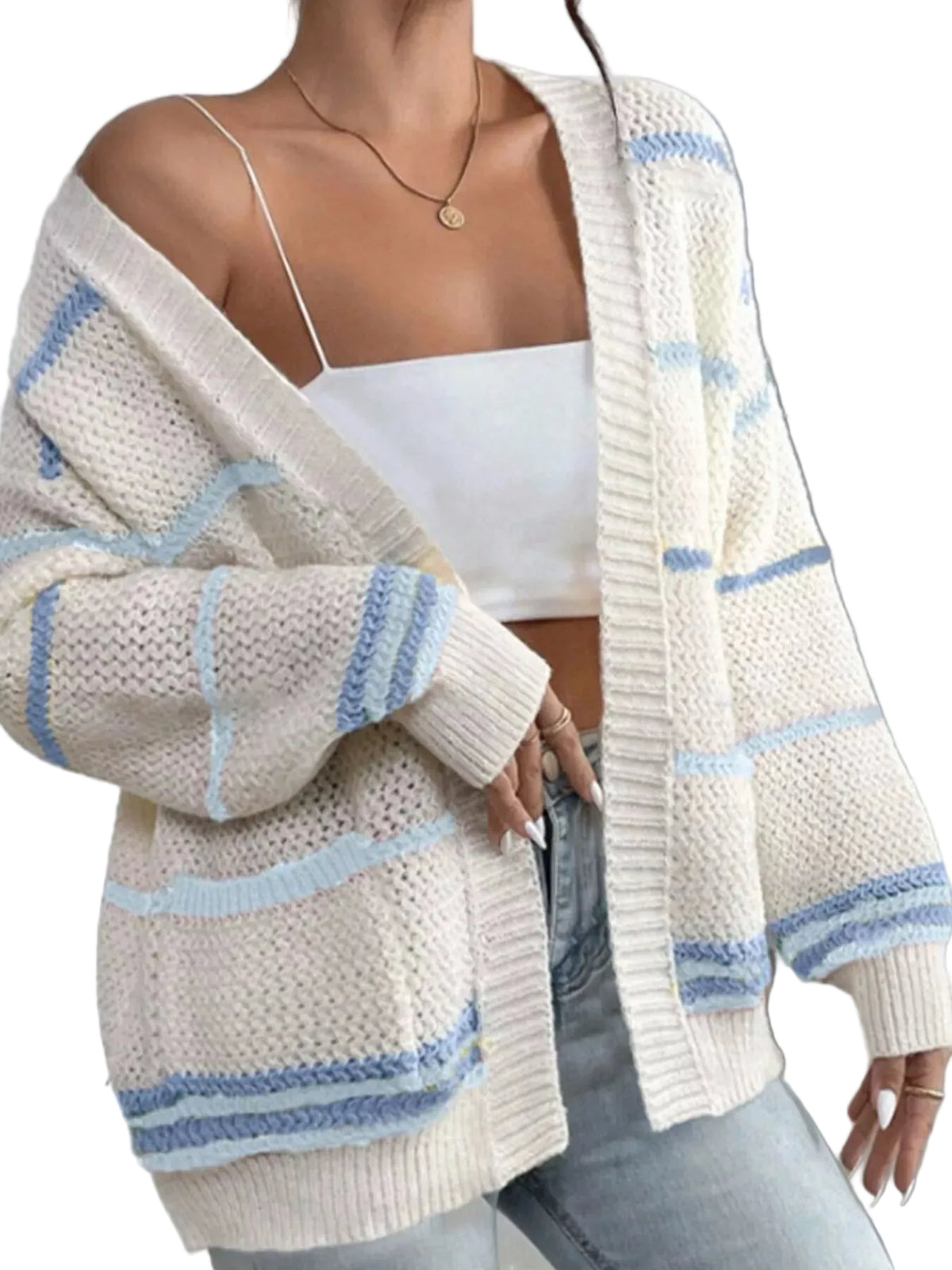 A woman wearing a chunky knit open-front cardigan in off-white with light blue stripes, layered over a white camisole and light-wash jeans.