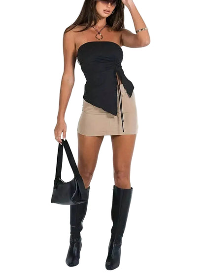 Woman wearing a black strapless top and beige skirt with black knee-high boots on a white background