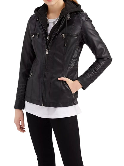 A woman wearing a black faux-leather hooded jacket with multiple zippered pockets, styled over a white shirt and black pants against a plain white studio background.