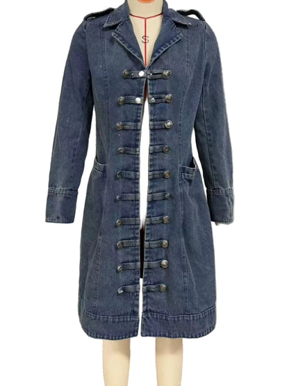 A blue denim military-style coat displayed on a mannequin, featuring a front zipper, decorative metal buttons, and shoulder epaulets, set against a window with horizontal blinds.