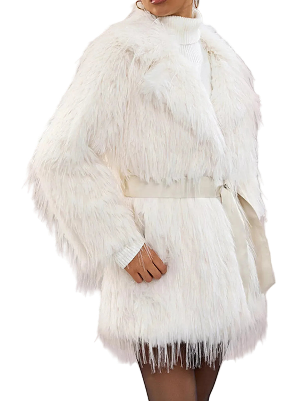 A model wearing a white faux fur coat with a matching belt over a white ribbed turtleneck sweater, set against a solid pale pink background.