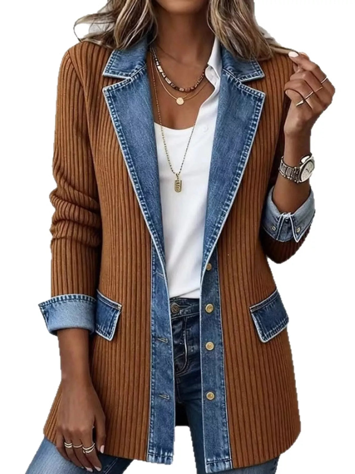A woman wearing a brown ribbed knit blazer-style jacket with blue denim lapels, pocket flaps, and button front, layered over a white top and blue jeans against a plain white background.