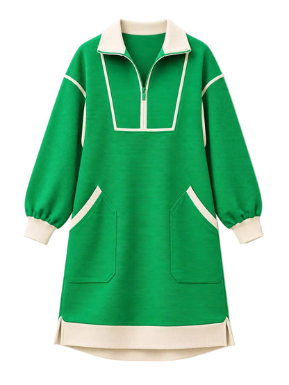 A green long-sleeve knit dress with cream-colored contrast panels, a half-zip collar, and front patch pockets, shown against a plain off-white background.
