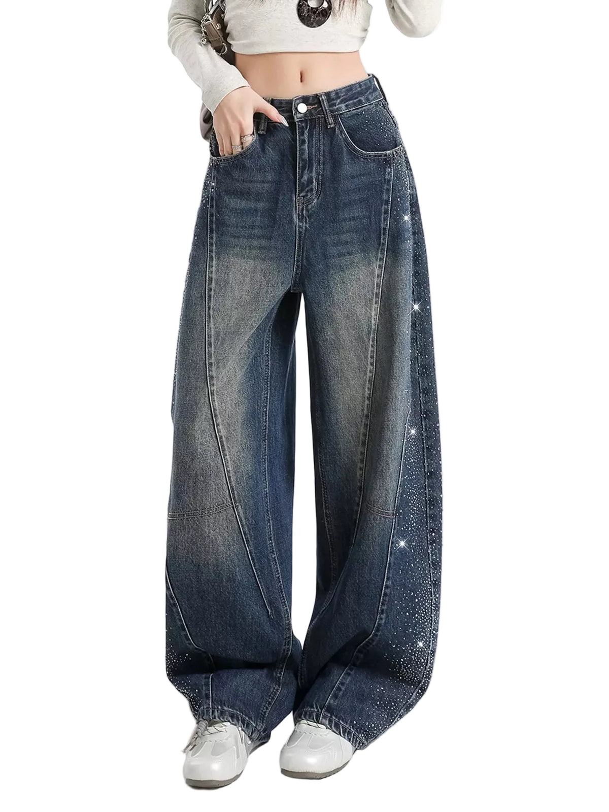 A person wearing very wide-leg dark blue denim jeans with faded wash details and small rhinestone embellishments down the outer seams, paired with a white cropped long-sleeve top and white sneakers against a plain white studio background.