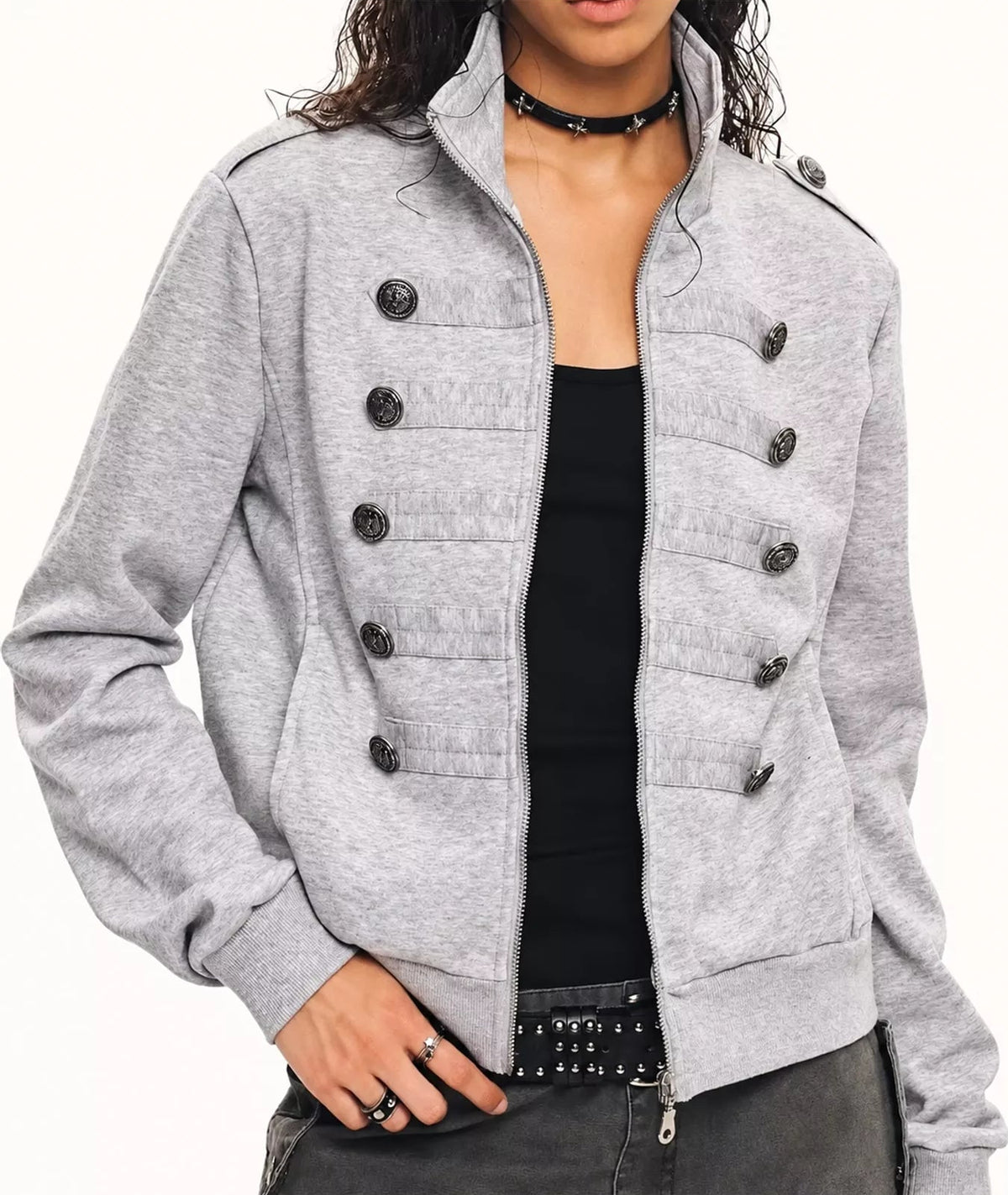 A woman wearing a light gray heathered double-breasted jacket with dark buttons, styled over a black top and dark gray pants.