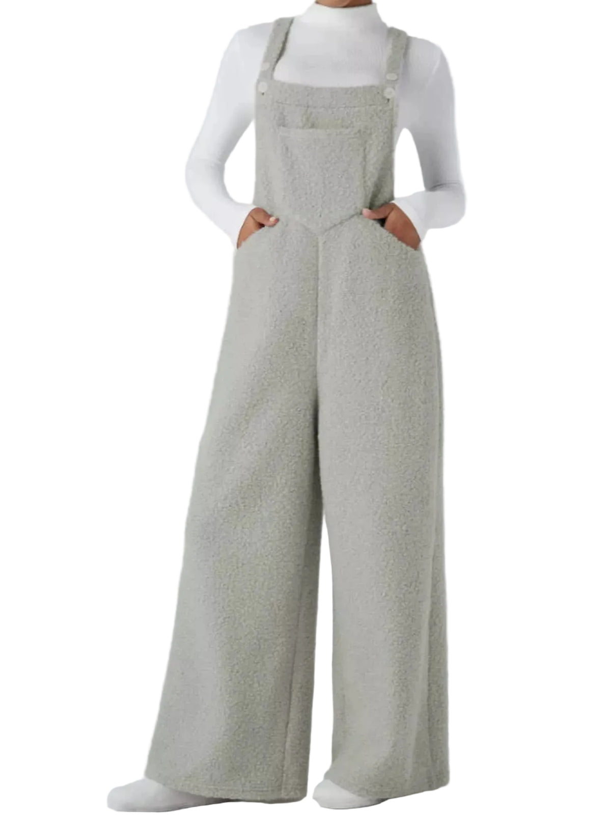 A model wearing light gray wide-leg overalls with a textured bouclé-like fabric, styled over a white long-sleeve top against a light gray studio background.