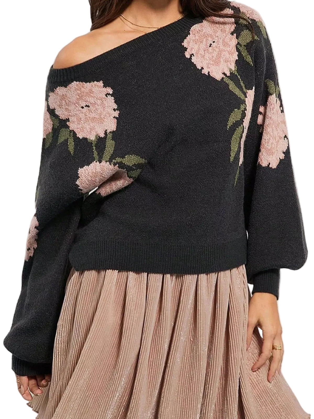 A woman wearing a dark charcoal off-the-shoulder knit sweater with large pink floral patterns and a pleated dusty pink skirt, shown against a plain light background.