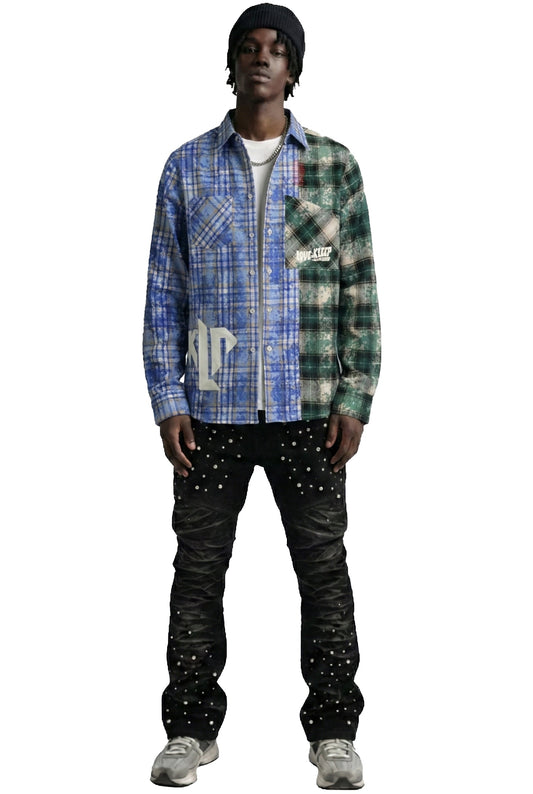 A model wearing a layered fashion outfit consisting of a blue and green plaid zip-up shirt, a white t-shirt, a black beanie, black studded cargo pants, and gray sneakers, isolated on a white background.