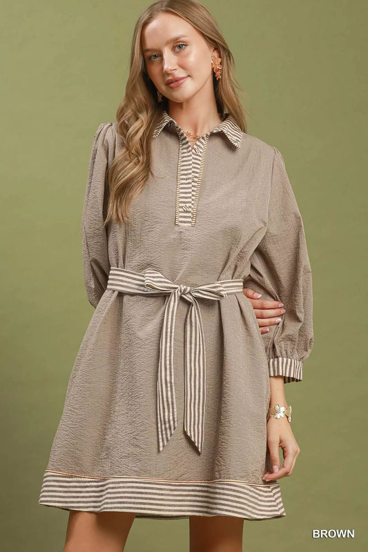 Woman wearing a brown dress with striped details on a green background