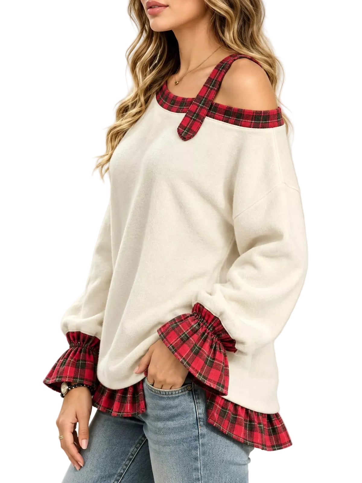 A woman wearing a cream-colored cold-shoulder sweater with red and green plaid trim at the neckline and cuffs, paired with blue jeans, against a plain light background.