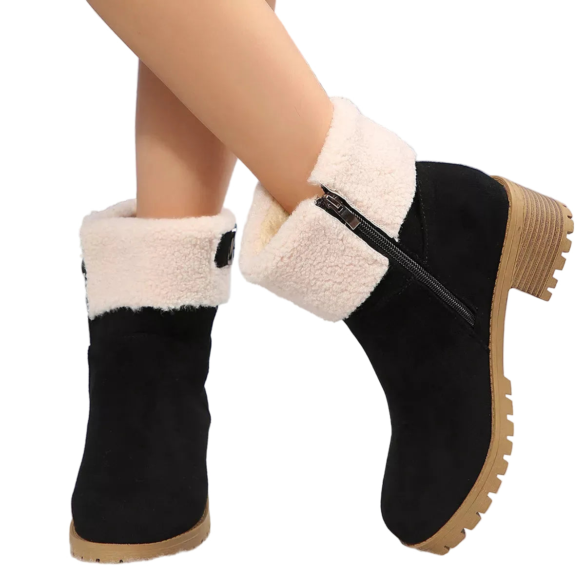 A pair of women's black suede ankle boots with thick cream sherpa fleece cuffs and tan soles, shown on a model's feet against a snowy background.