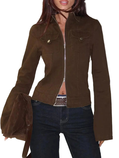 A woman wearing a cropped brown jacket with a front zipper, flap chest pockets, and dark blue jeans, holding a matching brown bag against a white studio background.