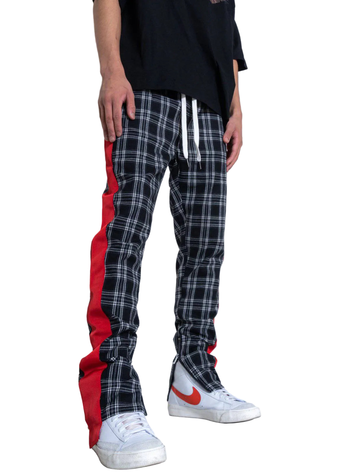Person wearing plaid pants with red accents and white sneakers on a plain background