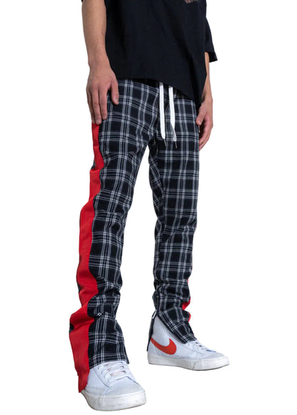 Person wearing plaid pants with red accents and white sneakers on a plain background