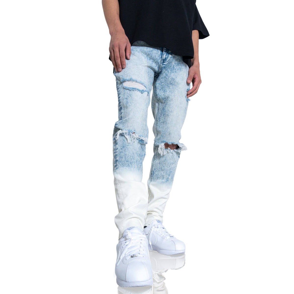 Person wearing light blue distressed jeans and white sneakers on a white background