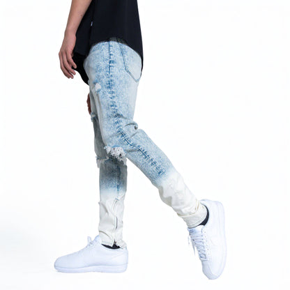 Person wearing light blue distressed jeans and white sneakers on a white background