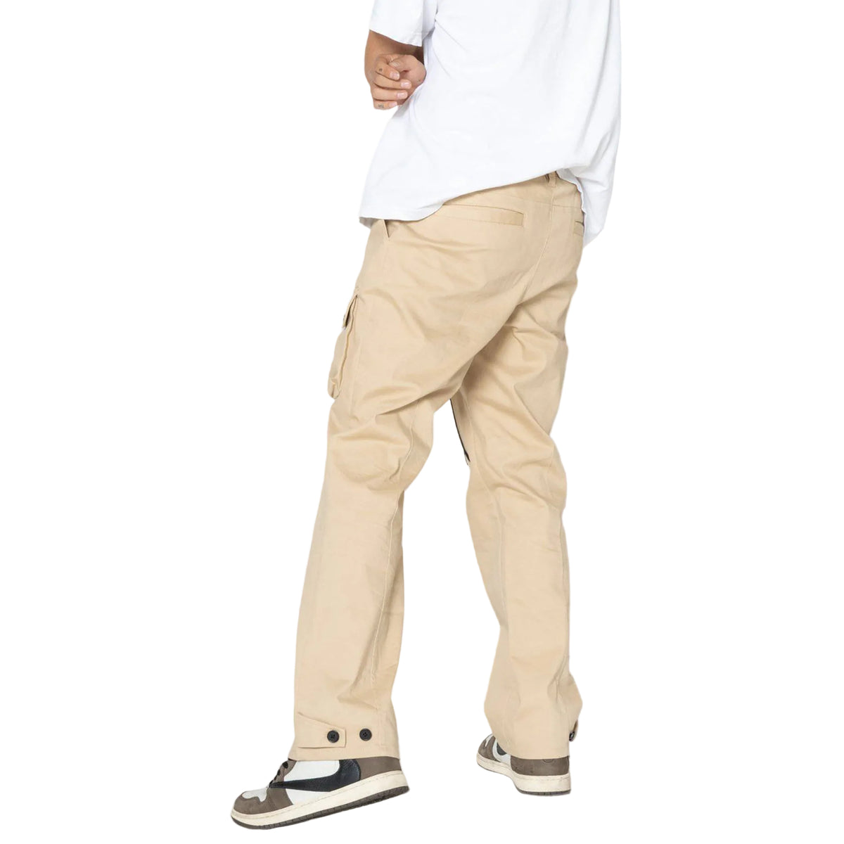 Person wearing beige pants and a white shirt on a plain background