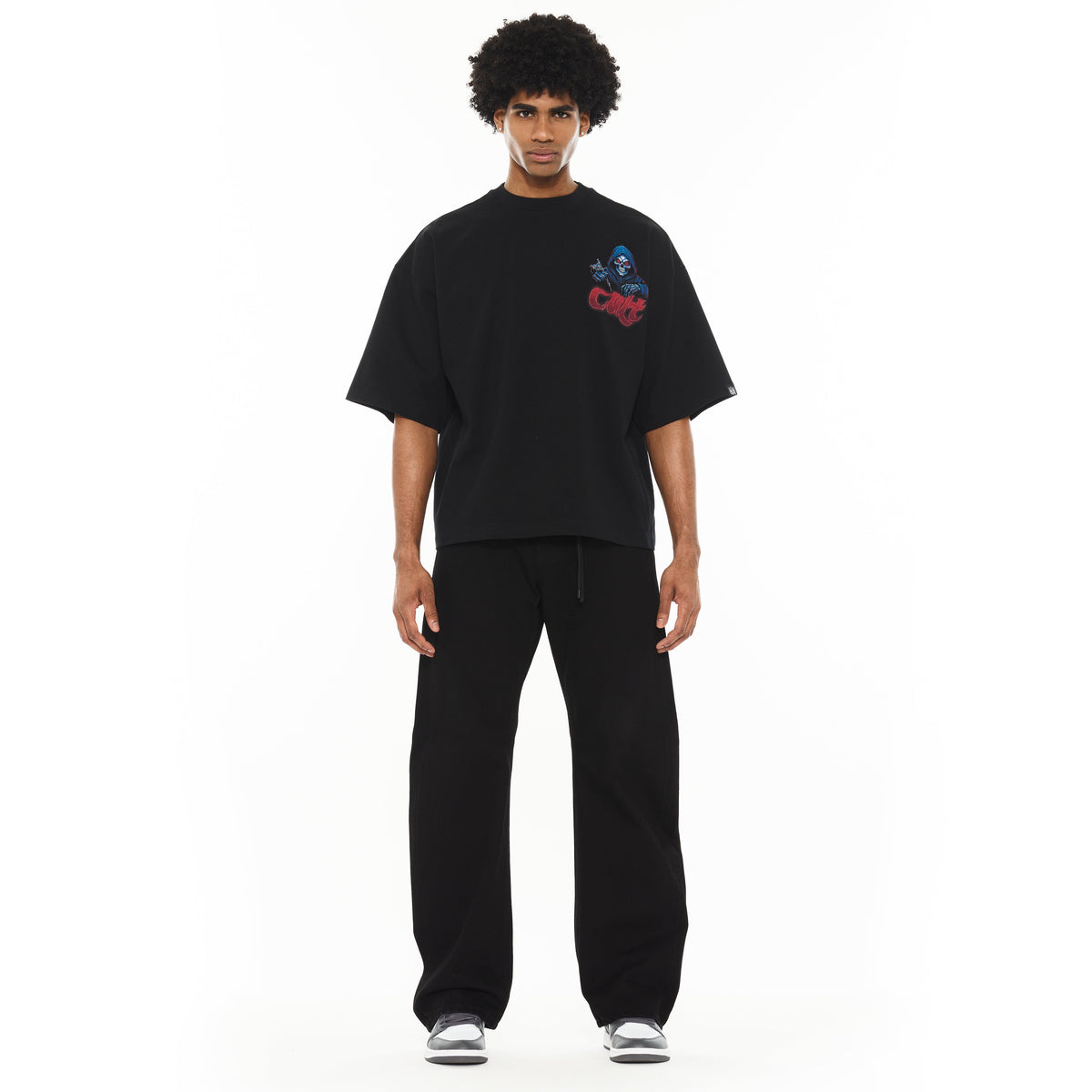 Person wearing a black oversized t-shirt with a graphic design on a white background
