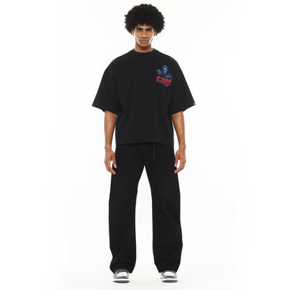 Person wearing a black oversized t-shirt with a graphic design on a white background