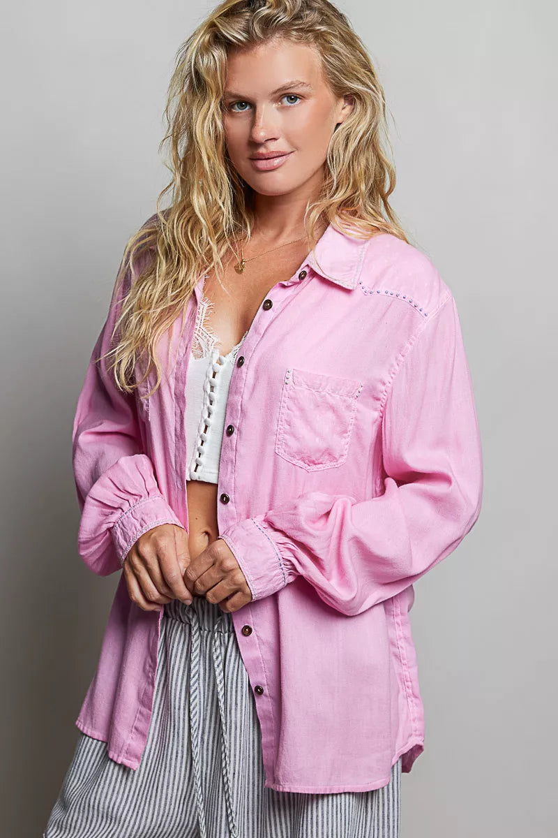 Woman wearing a pink denim jacket over a white top with a gray background