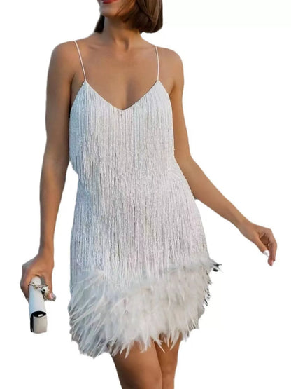 A woman wearing a white spaghetti-strap mini dress with a fringe upper bodice and a fluffy feathered hem, holding a small white handbag against a plain white background.