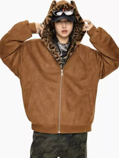 A person wearing a brown zip-up hooded jacket with a leopard-print inner hood lining, a black cap, and camouflage pants, posed against a plain light background.