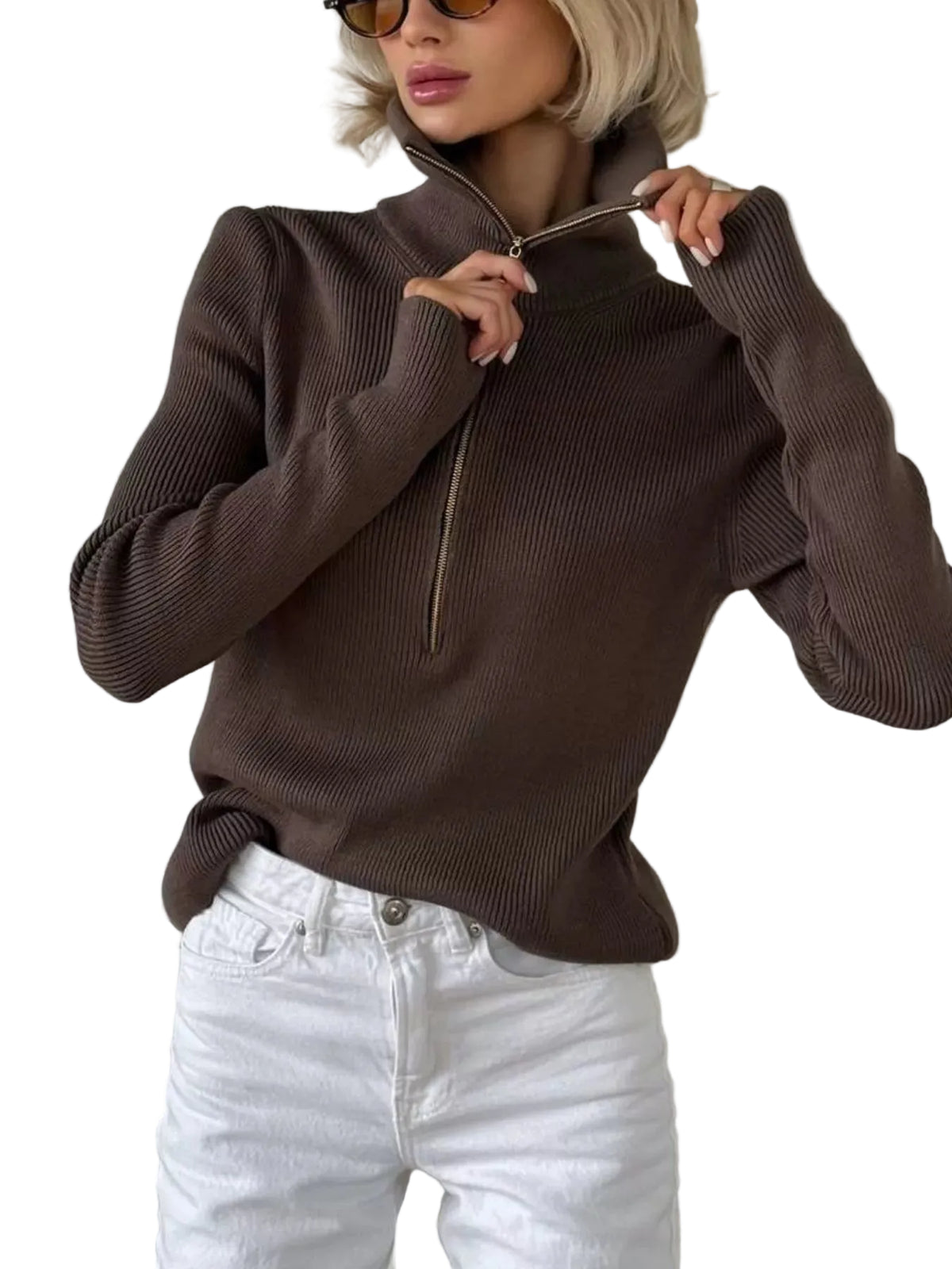 A woman wearing a dark brown ribbed knit half-zip mock-neck sweater and white jeans, standing indoors against a light-colored wall.