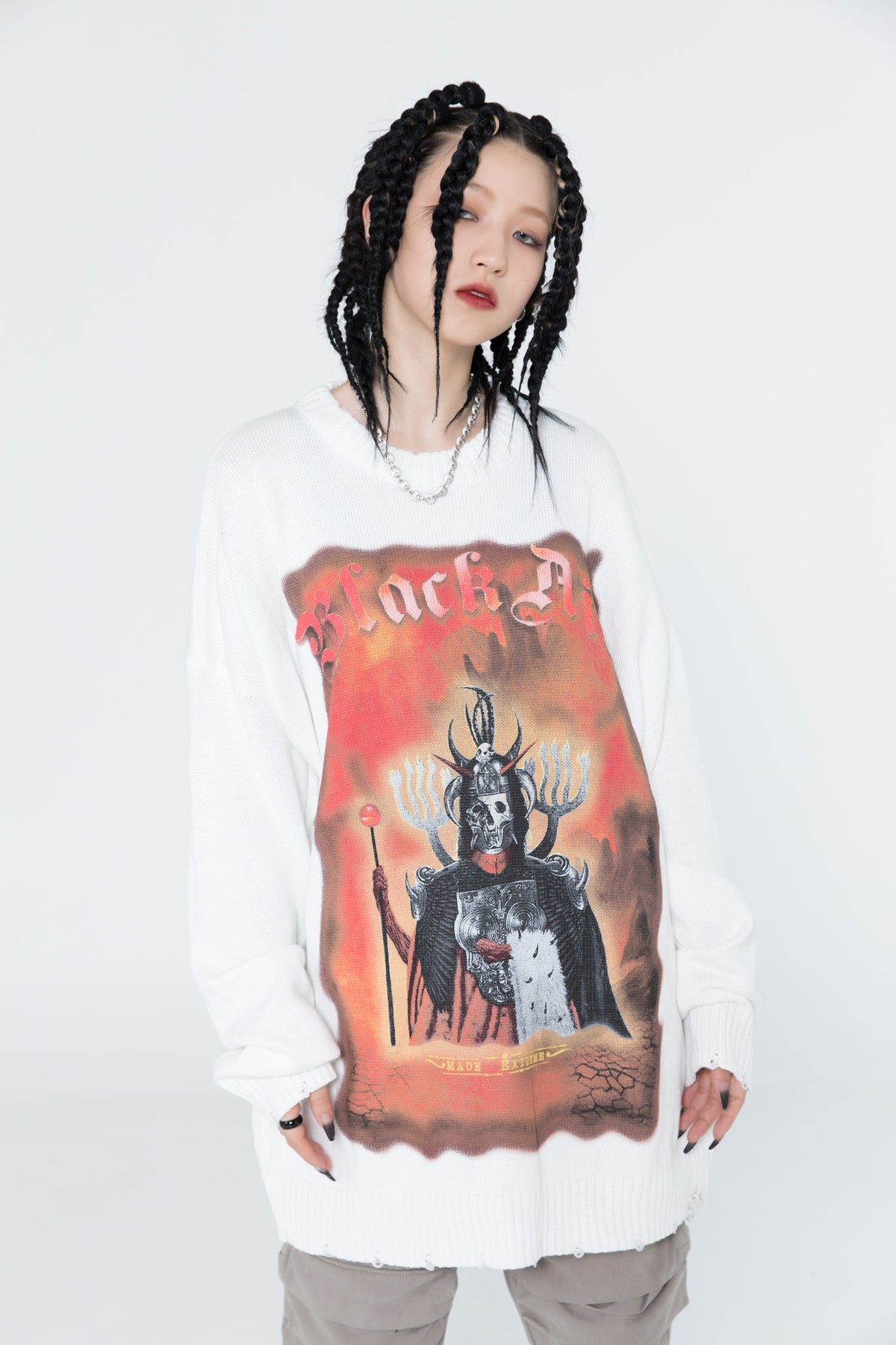 Person wearing a white sweatshirt with a graphic design on a plain background