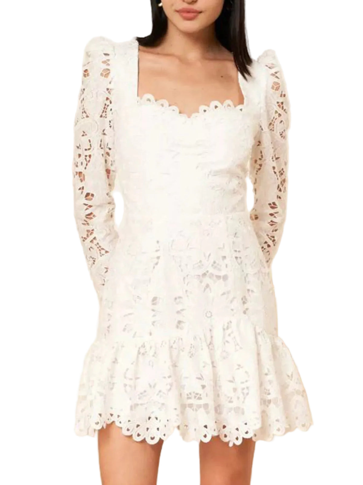 A woman wearing a white eyelet lace mini dress with long sheer sleeves, a sweetheart neckline, and a ruffled hem, shown against a light beige wall.