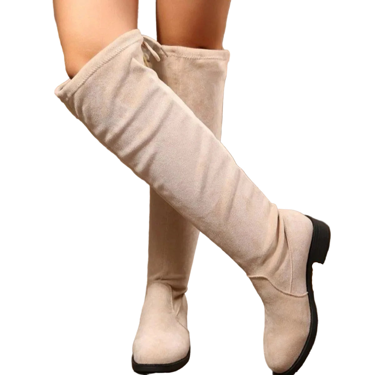 A person wearing knee-high beige suede-like boots with a drawstring detail at the top, standing on a wooden surface in front of hay bales and rope.