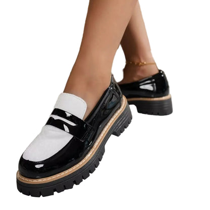Black and white patent leather platform loafers with chunky lug soles, shown on a model's feet.