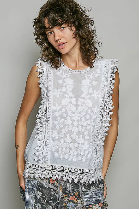 Woman wearing a sleeveless top with lace details against a plain background