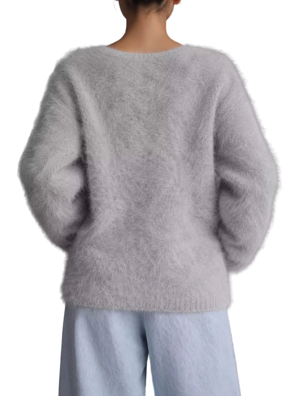 A person shown from the back wearing a fuzzy light gray knit sweater and pale blue pants against a plain gray studio background.