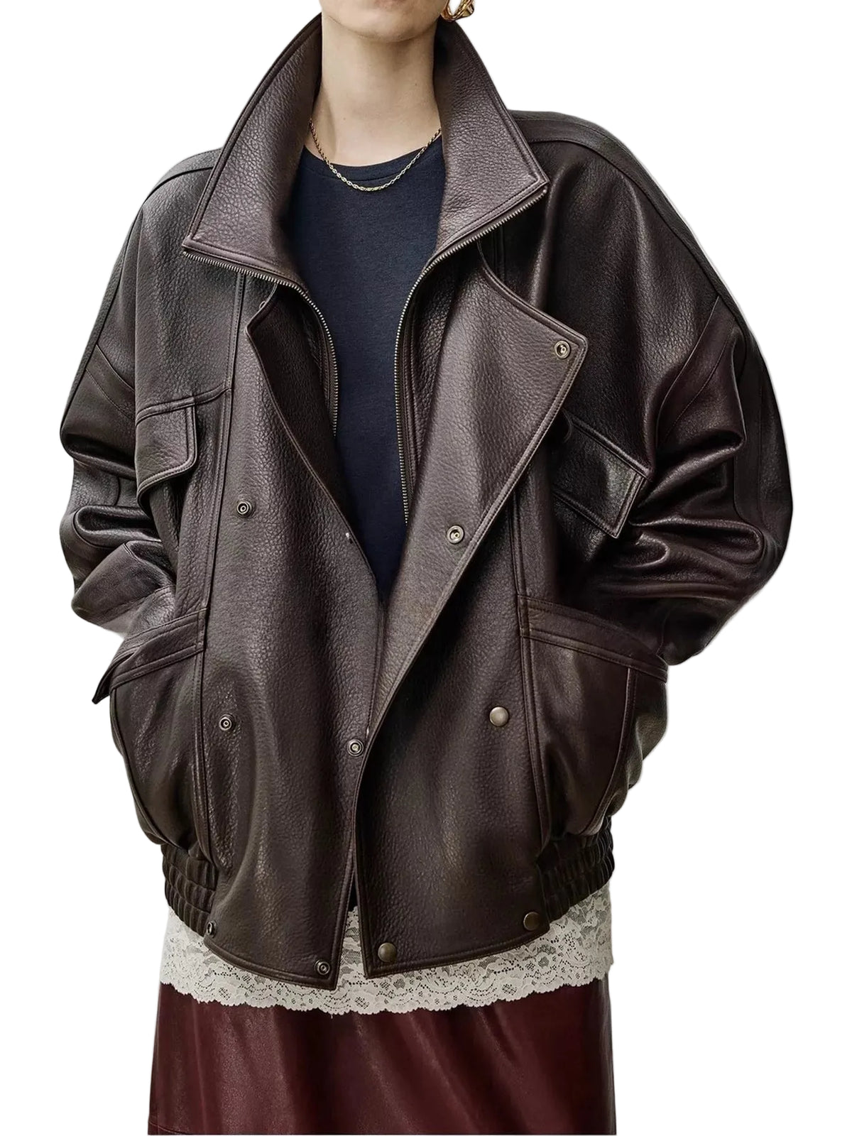 A person wearing an oversized dark brown leather jacket with a high collar, asymmetrical snap closure, and front flap pockets, layered over a navy top and burgundy skirt against a light gray studio background.