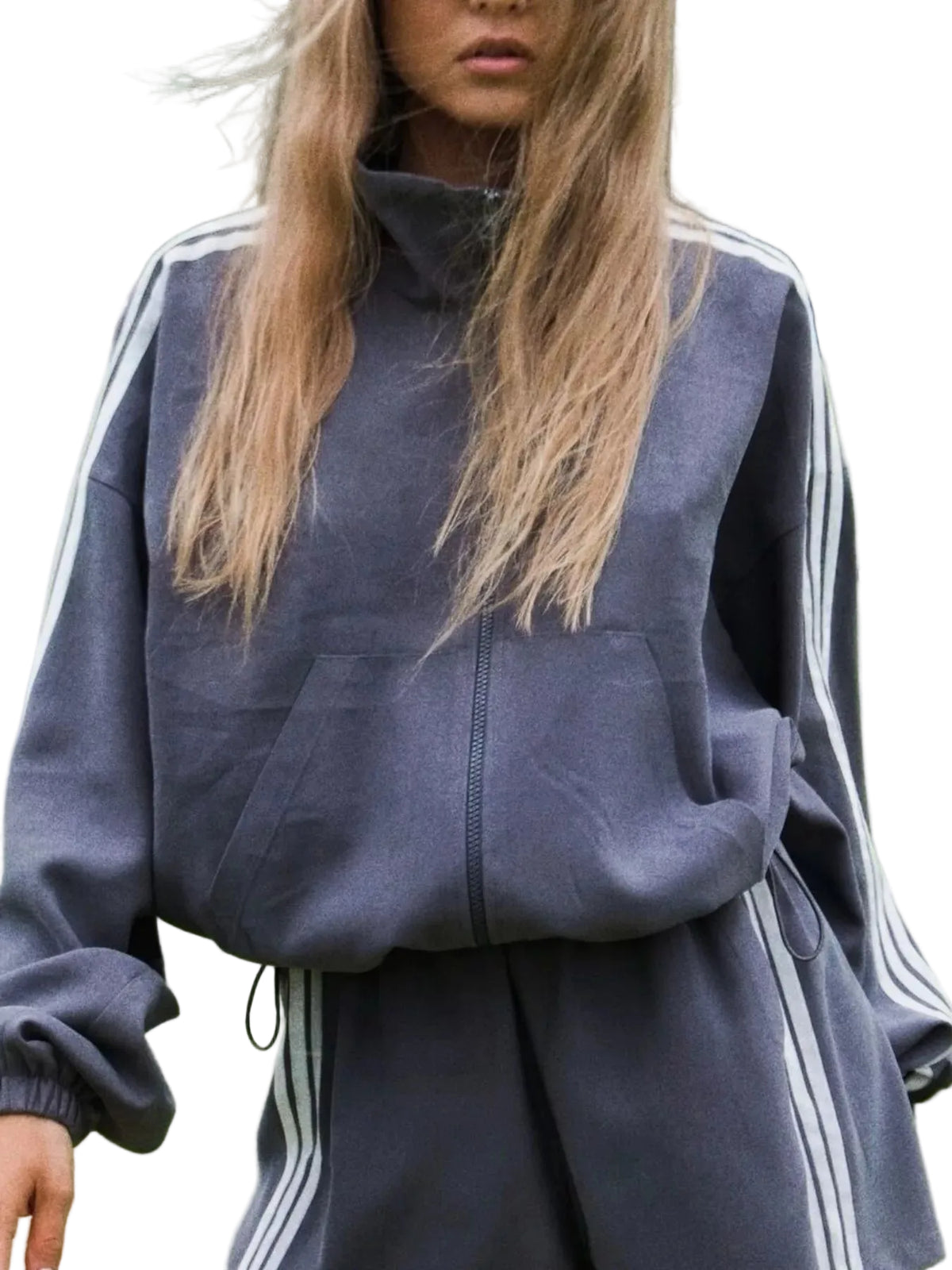 A woman wearing a dark slate blue full-zip track jacket with white stripes on the shoulders and sleeves, standing on a green tennis court.