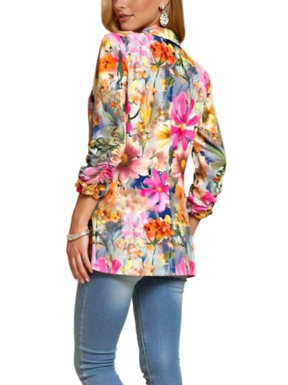 A woman wearing a colorful floral long-sleeve button-up shirt and blue jeans, shown from a side-back angle against a plain beige studio background.
