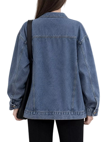 A person shown from the back wearing an oversized blue denim jacket with black pants and a black shoulder bag, photographed against a plain light background.