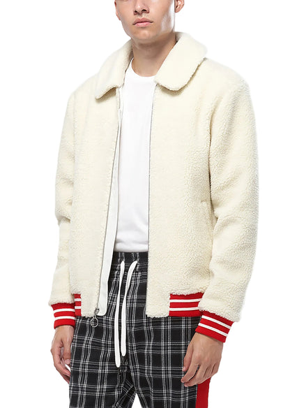 Person wearing a cream sherpa jacket with red accents on a white background