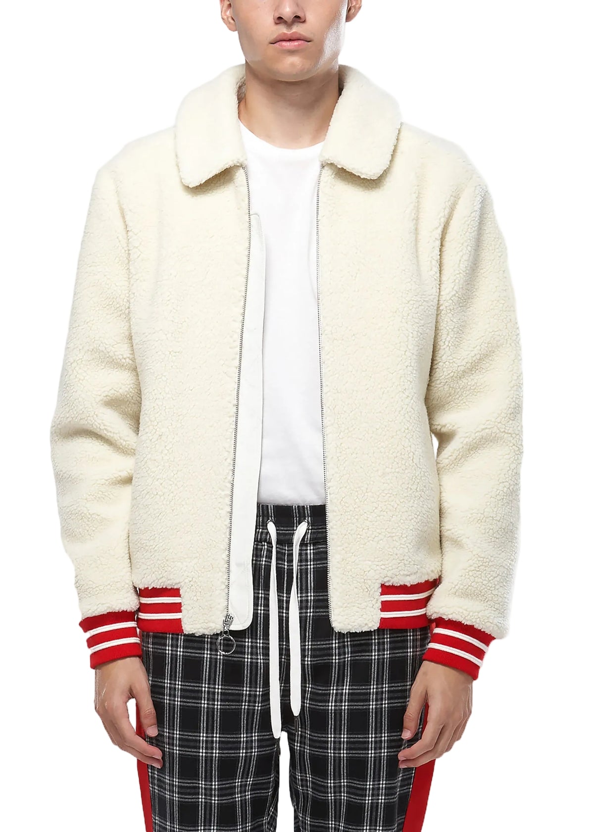 Person wearing a cream-colored cardigan with red trim, white shirt, and plaid pants on a white background