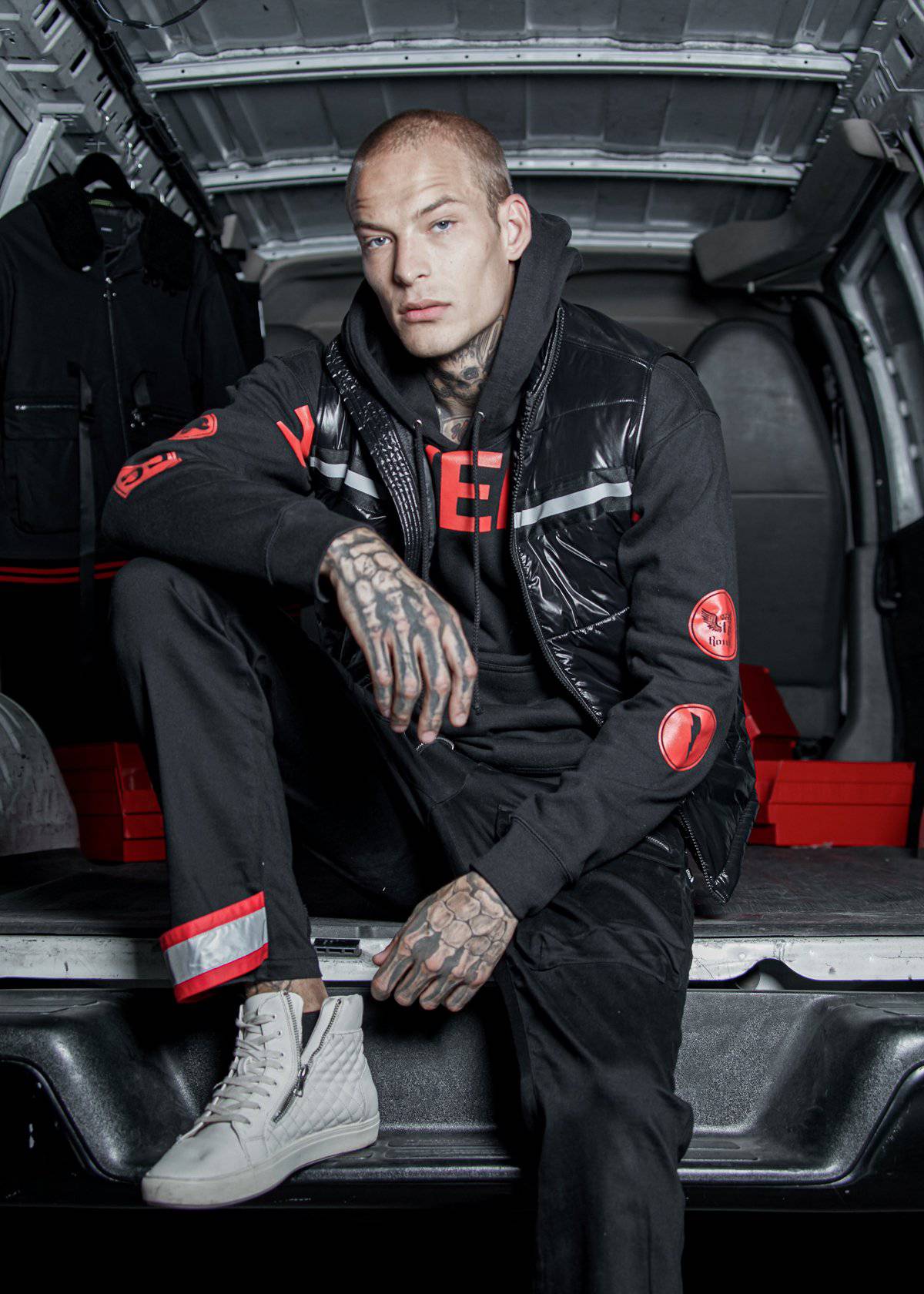 Person wearing a black jacket with red accents sitting inside a vehicle.