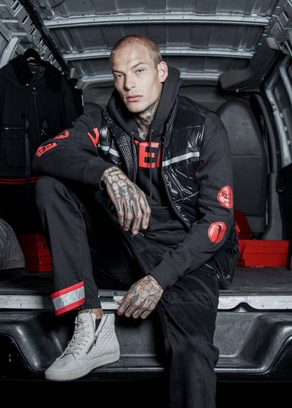 Person wearing a black jacket with red accents sitting inside a vehicle.