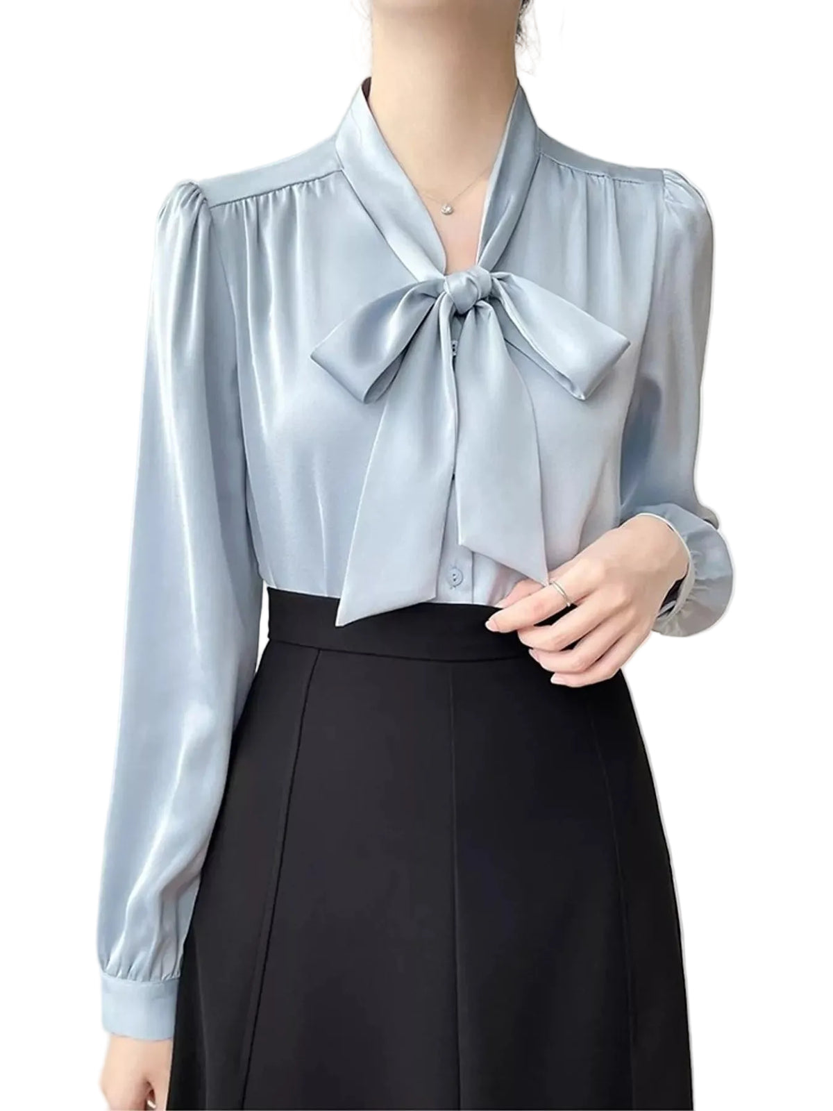 A woman wearing a light blue satin blouse with a large bow at the collar and a black skirt, shown from the neck down against a plain light background.