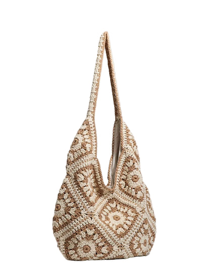A handmade crochet shoulder bag in beige and cream, featuring intricate geometric patterns and a single shoulder strap, set against a plain light gray background.