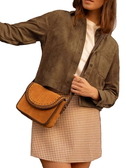 A woman wearing a brown suede cropped jacket, a brown and white gingham mini skirt, and a white top, carrying a brown suede crescent-shaped crossbody bag with a dark strap.
