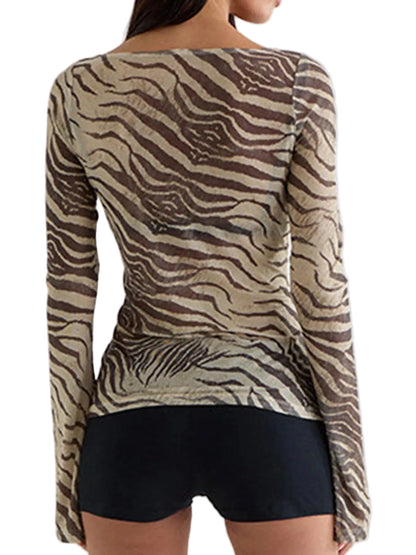 A woman shown from the back wearing a beige and brown zebra-print long-sleeve top with black shorts against a light gray studio background.
