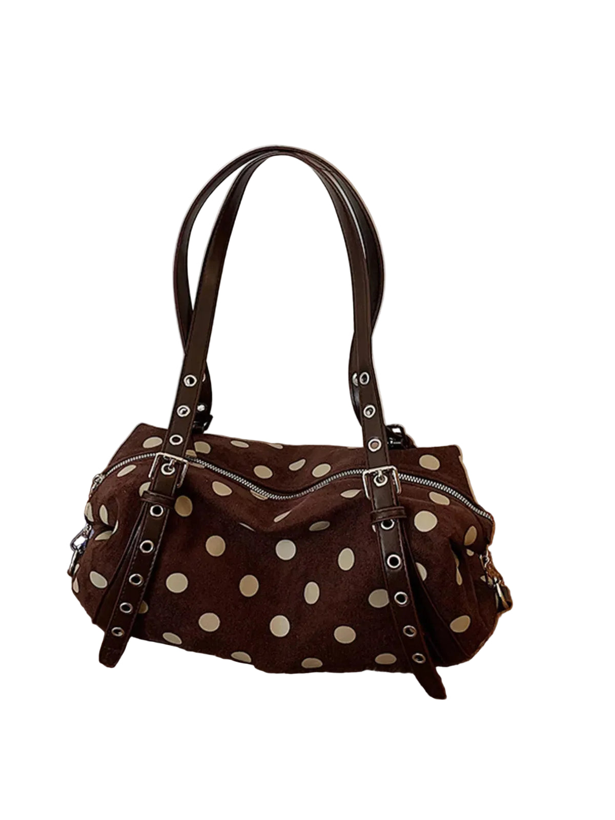 A brown suede handbag with cream polka dots and dark brown leather straps, resting on a wooden floor against a white paneled wall.